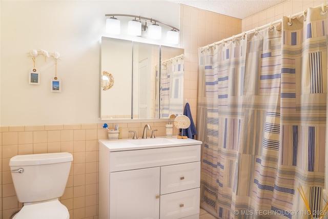 full bath with vanity, a shower with curtain, a textured ceiling, tile walls, and toilet