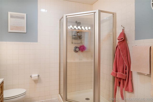 full bath featuring a shower stall, tile walls, vanity, and toilet