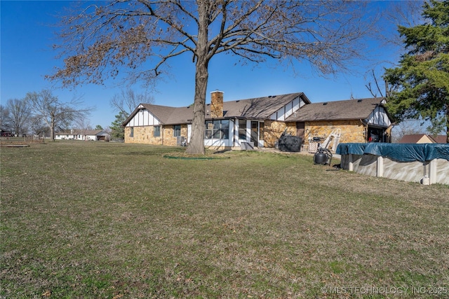 rear view of house featuring a covered pool, a lawn, a chimney, and a sunroom