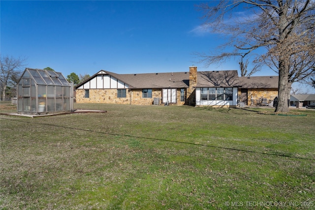 rear view of property featuring an outdoor structure, a yard, a chimney, and an exterior structure