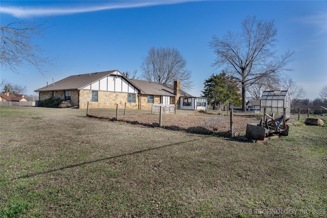 view of home's exterior with a yard, stone siding, and fence