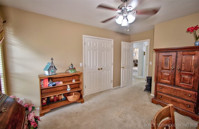 bedroom with a closet, baseboards, light colored carpet, and ceiling fan