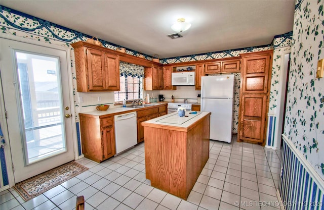 kitchen with white appliances, visible vents, light tile patterned flooring, a sink, and a center island