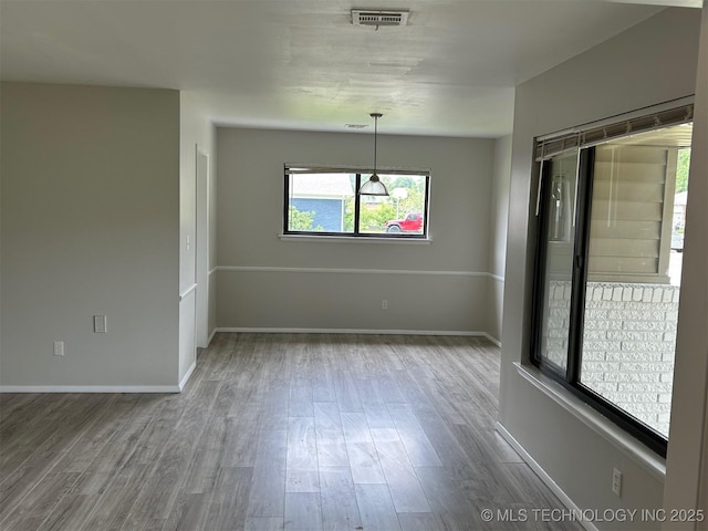 unfurnished room with visible vents, baseboards, and wood finished floors