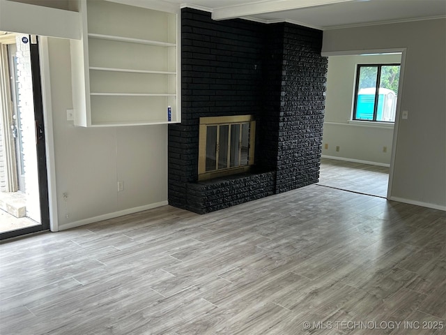 unfurnished living room featuring a fireplace, wood finished floors, baseboards, and ornamental molding