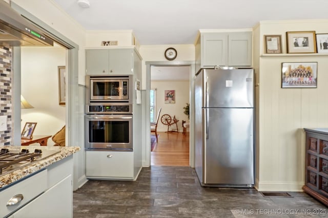 kitchen featuring dark wood-style floors, light stone countertops, ornamental molding, stainless steel appliances, and backsplash