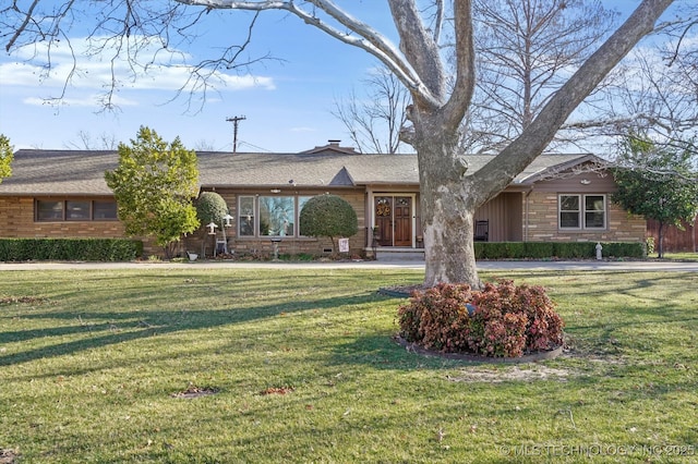 ranch-style house featuring a chimney, a front lawn, and roof with shingles