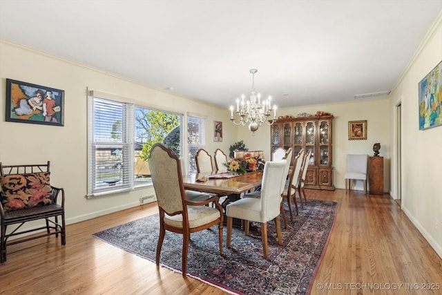 dining room with a notable chandelier, baseboards, light wood finished floors, and ornamental molding