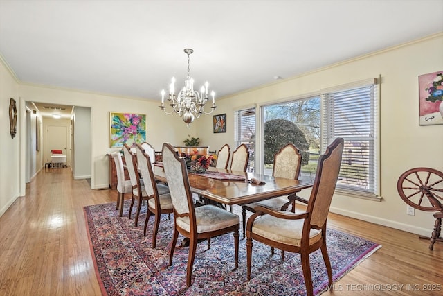 dining space with light wood-style flooring, a notable chandelier, plenty of natural light, and ornamental molding