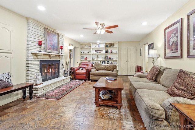 living area featuring recessed lighting, built in shelves, a fireplace, and a ceiling fan