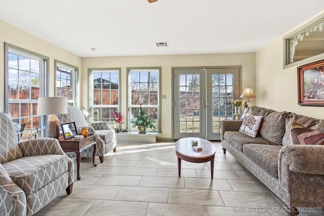 living area with a healthy amount of sunlight, visible vents, and french doors