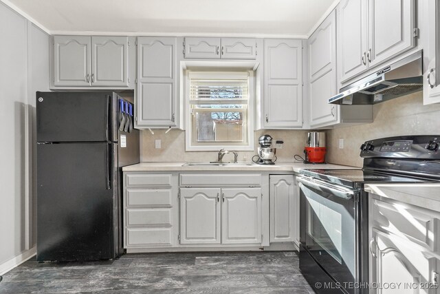 kitchen with electric range, freestanding refrigerator, a sink, light countertops, and under cabinet range hood
