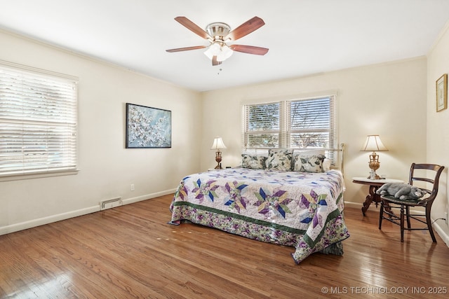 bedroom featuring ceiling fan, wood finished floors, visible vents, and baseboards