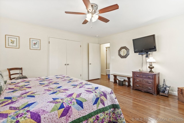 bedroom with a closet, baseboards, wood finished floors, and a ceiling fan