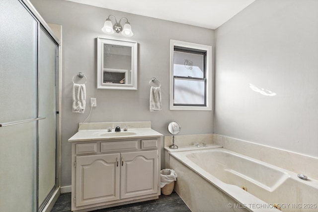 full bathroom featuring vanity, a tub with jets, and a stall shower