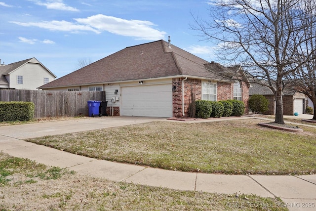 view of home's exterior with brick siding, fence, a lawn, a garage, and driveway