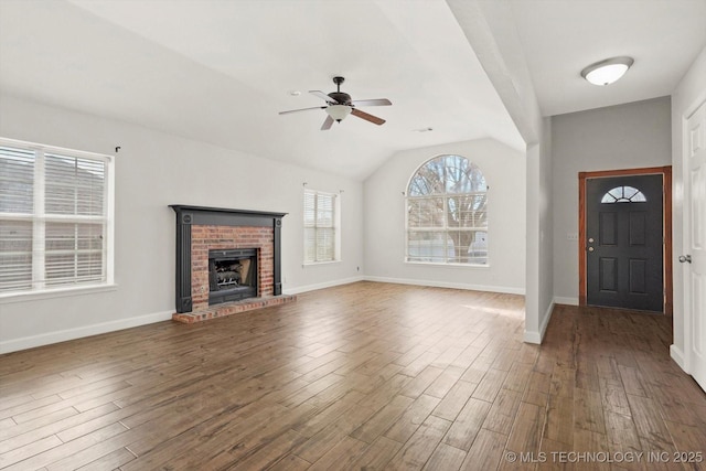 entryway with a ceiling fan, wood finished floors, baseboards, a brick fireplace, and vaulted ceiling