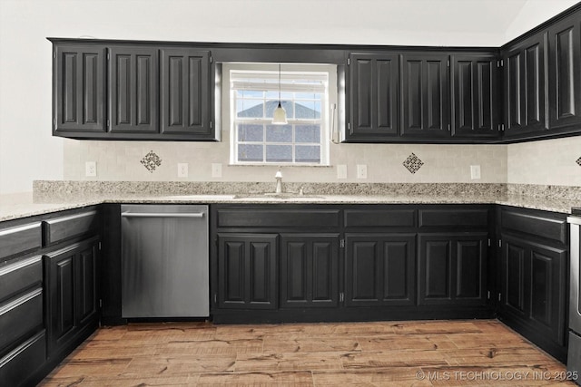 kitchen with light wood-style flooring, a sink, light stone counters, dark cabinetry, and dishwasher