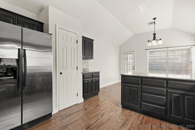 kitchen featuring visible vents, wood finished floors, stainless steel fridge, a chandelier, and dark cabinets