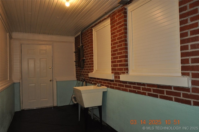 hallway featuring brick wall, wooden ceiling, and a sink