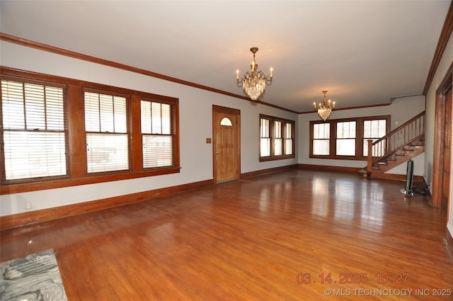 unfurnished living room with baseboards, a notable chandelier, wood finished floors, and ornamental molding