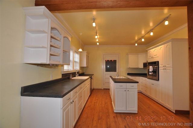 kitchen featuring dark countertops, a kitchen island, oven, light wood-type flooring, and a sink