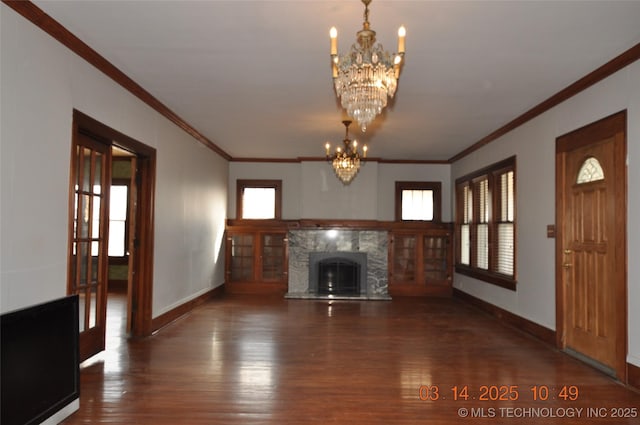 unfurnished living room featuring a notable chandelier, ornamental molding, wood finished floors, a fireplace, and baseboards