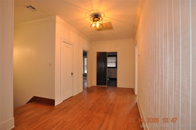 hall featuring visible vents, wood finished floors, and crown molding