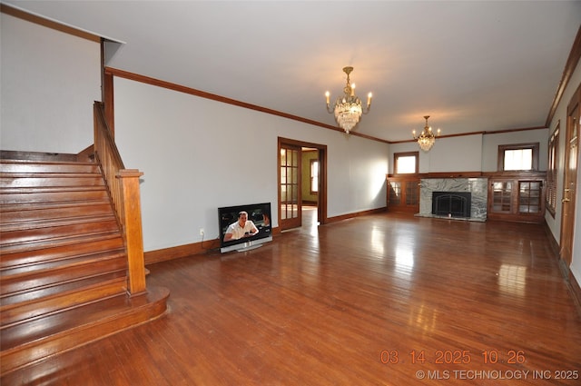 unfurnished living room featuring a fireplace, baseboards, an inviting chandelier, and wood finished floors