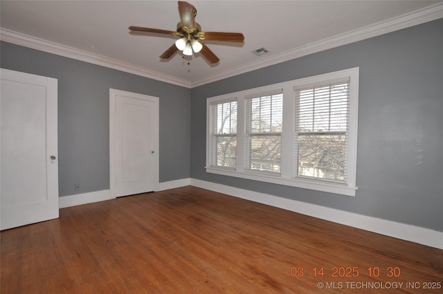 spare room with visible vents, a ceiling fan, wood finished floors, crown molding, and baseboards