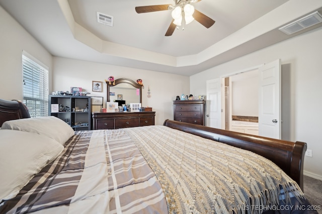 carpeted bedroom with baseboards, visible vents, a ceiling fan, and a tray ceiling