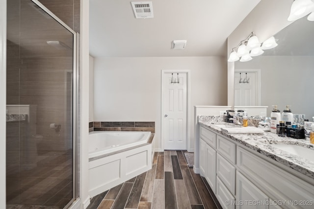 bathroom featuring a shower stall, a bath, visible vents, and wood finish floors