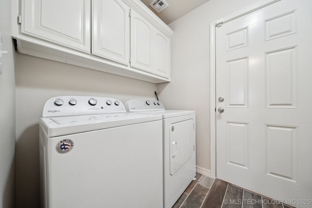 laundry area with baseboards, visible vents, wood finish floors, cabinet space, and washing machine and dryer