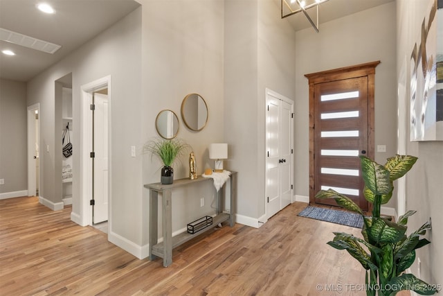 foyer entrance featuring recessed lighting, baseboards, a high ceiling, and light wood-style flooring