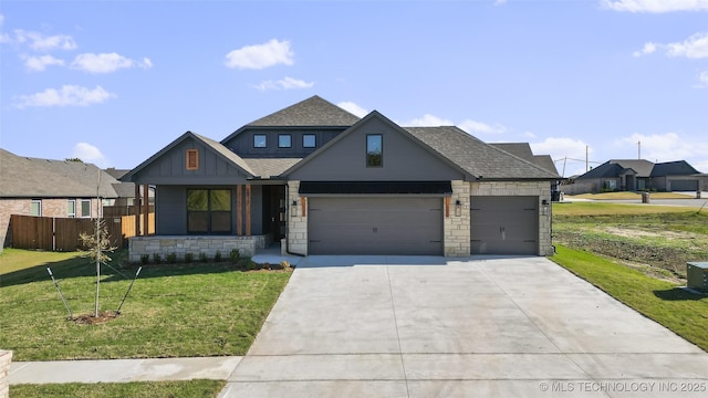 view of front of home with fence, driveway, a shingled roof, a front lawn, and stone siding