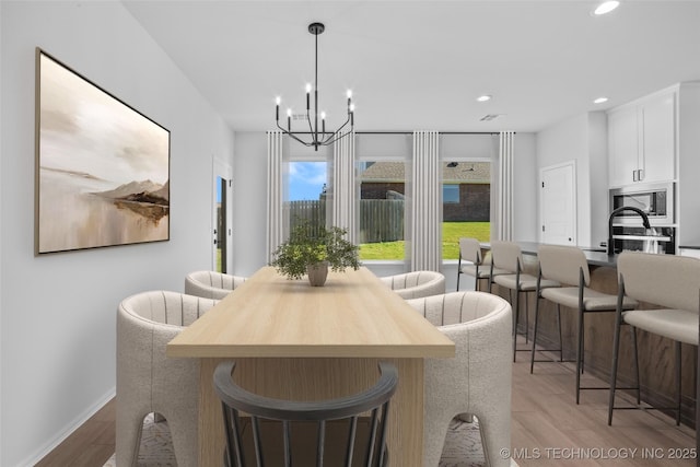 dining space with a notable chandelier, light wood-style floors, recessed lighting, and baseboards