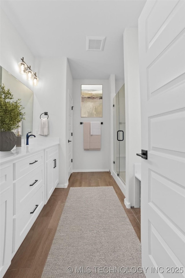 full bathroom with visible vents, a stall shower, vanity, and wood finished floors