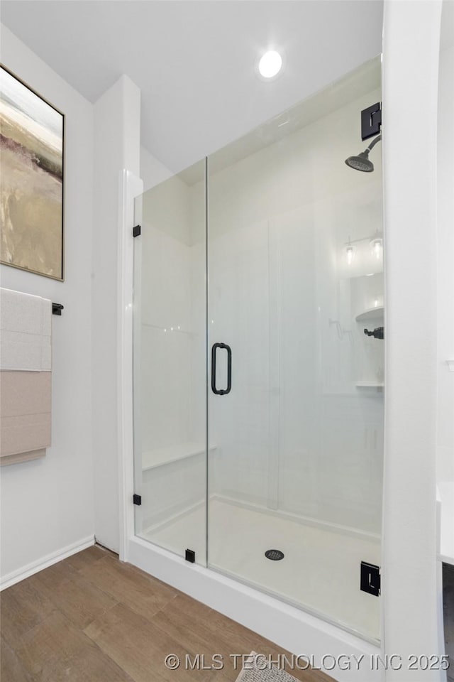 bathroom with wood finished floors and a stall shower