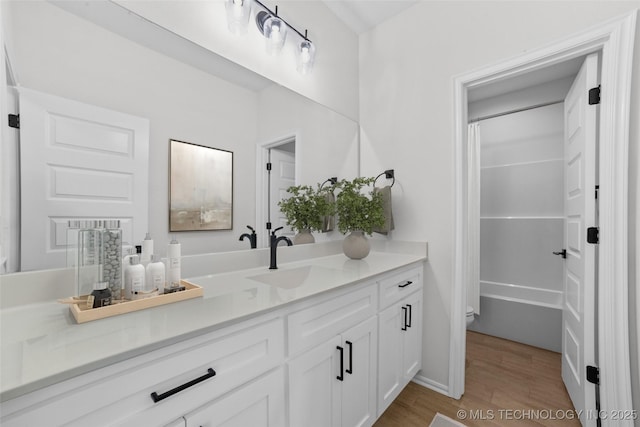 bathroom with vanity, toilet, wood finished floors, and shower / bath combo