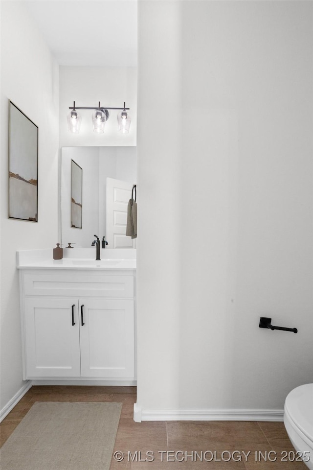 bathroom featuring baseboards, toilet, and vanity