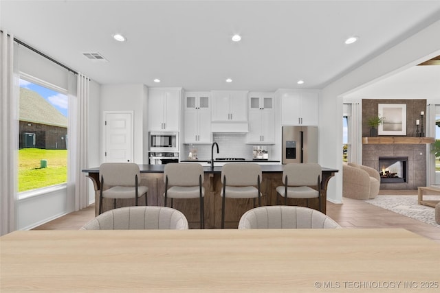 kitchen with tasteful backsplash, visible vents, a kitchen bar, an island with sink, and stainless steel appliances