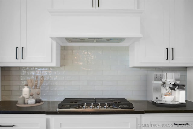 kitchen with white cabinetry, dark countertops, stainless steel gas stovetop, and custom range hood