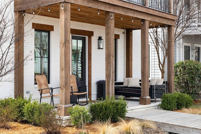 view of exterior entry with brick siding and covered porch