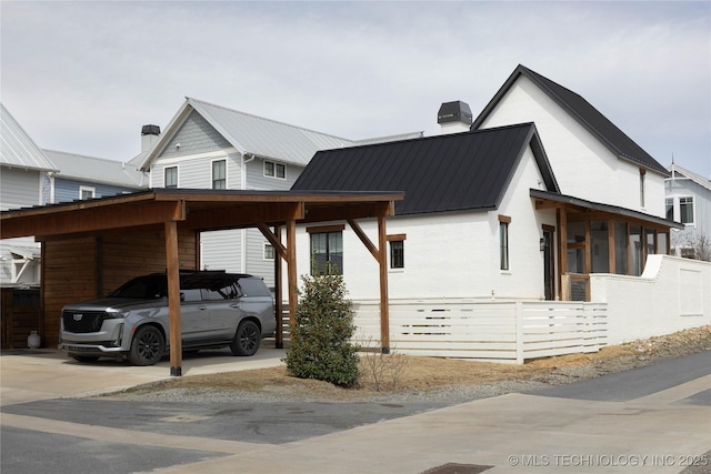 view of front of property with brick siding, driveway, an attached carport, and a chimney