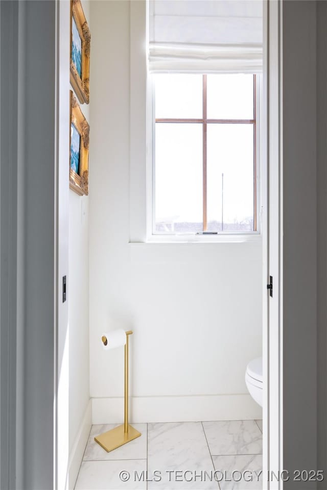 bathroom featuring baseboards, toilet, and marble finish floor