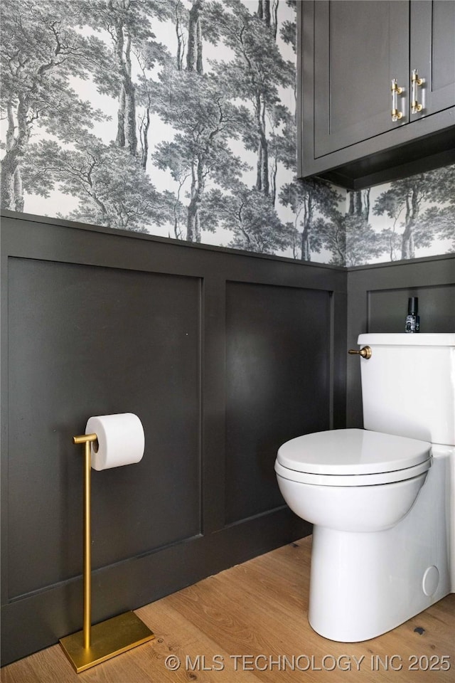 bathroom featuring toilet, wood finished floors, and wainscoting