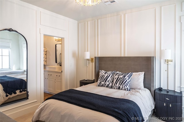 bedroom featuring a chandelier, visible vents, and ensuite bathroom