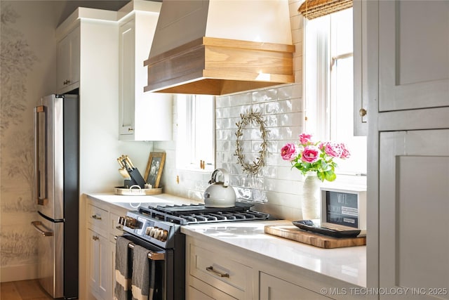 kitchen featuring light countertops, premium range hood, backsplash, and stainless steel appliances