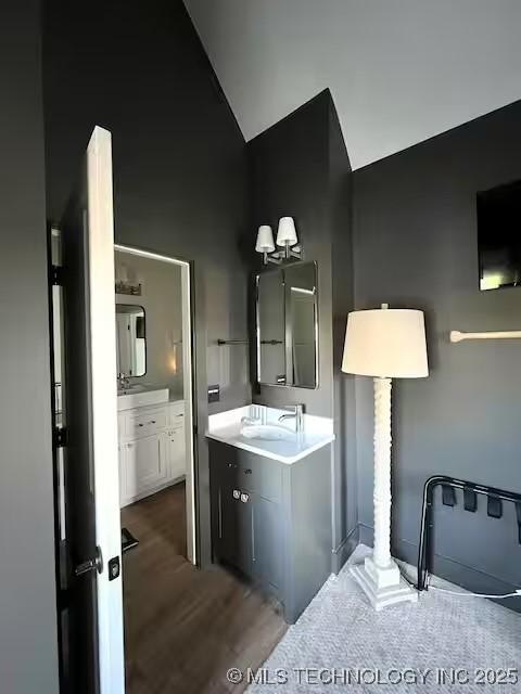 bathroom featuring wood finished floors, vanity, and vaulted ceiling