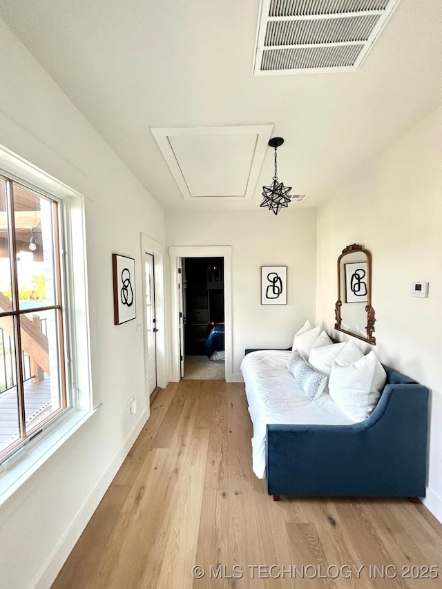 bedroom featuring visible vents, baseboards, attic access, and light wood finished floors